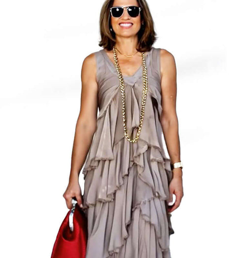 Elegant long beige chiffon dress with subtle pleats, model wearing sunglasses and a red handbag.